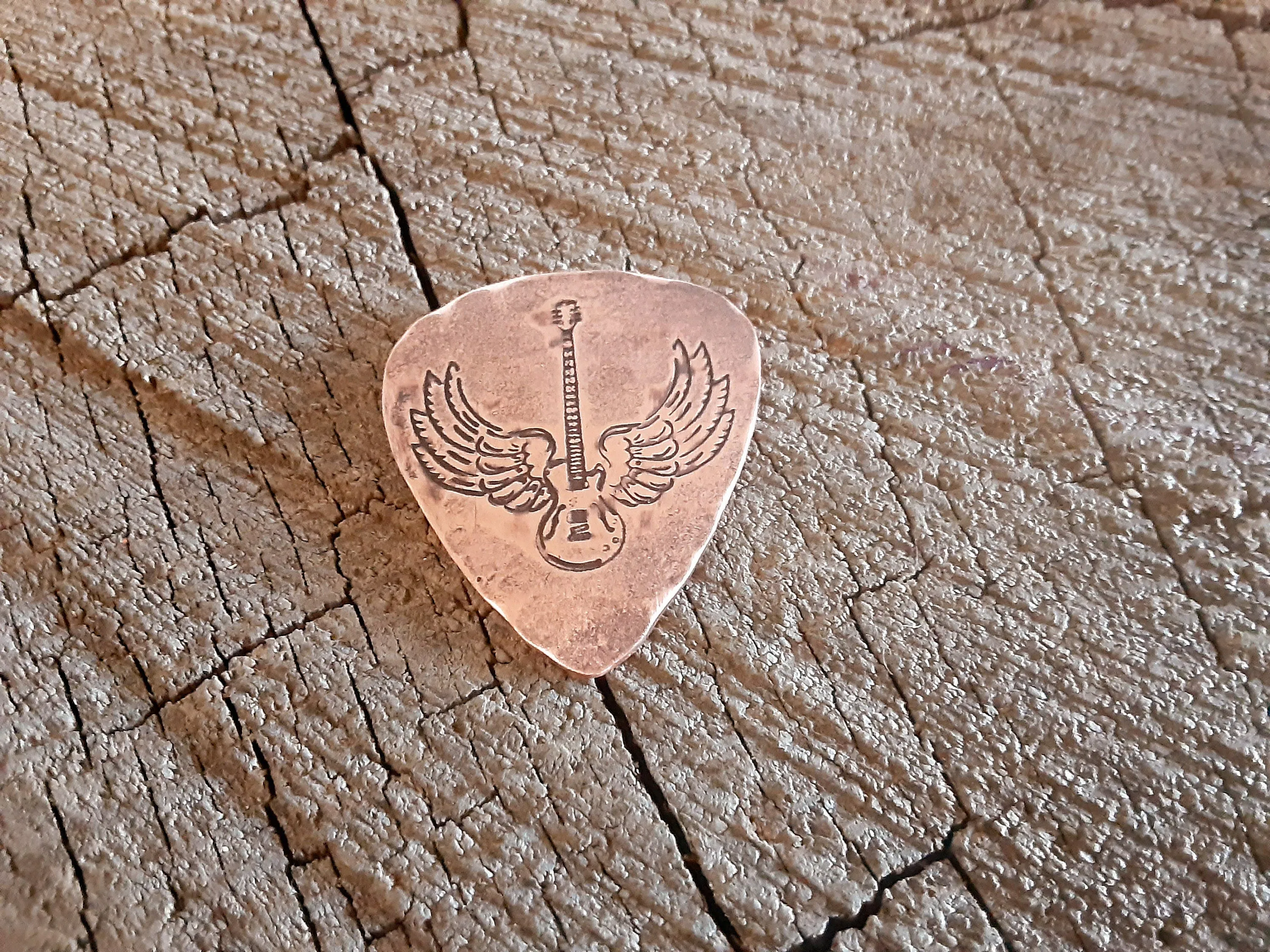 Winged guitar on copper guitar pick