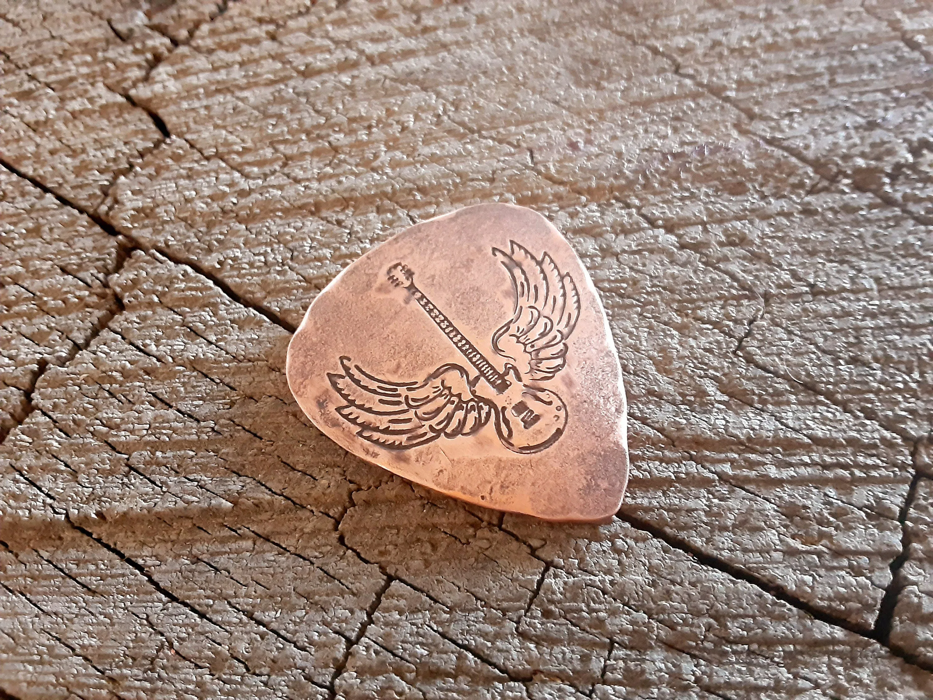 Winged guitar on copper guitar pick